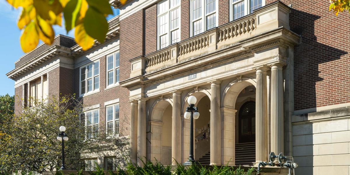 A view of the front entrance of Campbell Hall from diagonal of the building. Leaves are seen on the top of the photo as if the photograph was taken from under a tree.