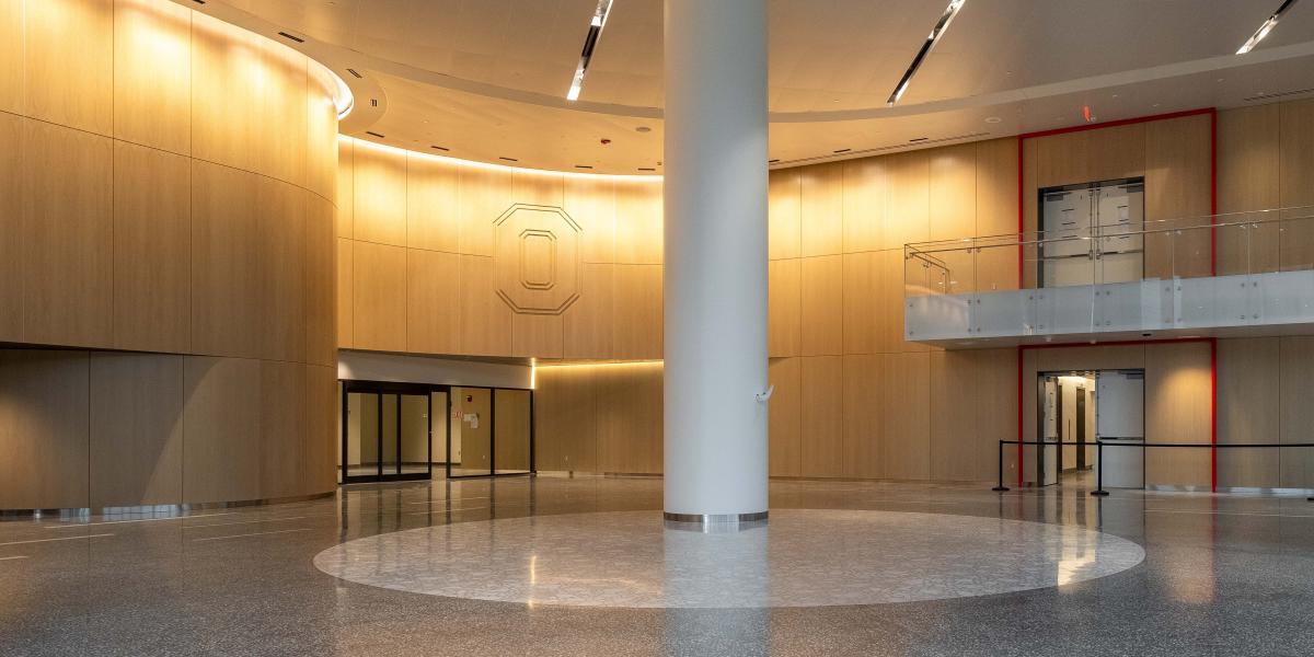 A view of the lobby where Terrazzo floors are seen finished with a large Block O on wood near the ceiling. 